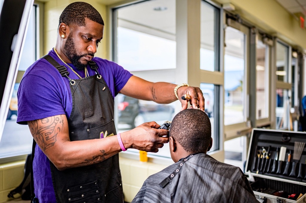 Barber in an apron working on a client's fade