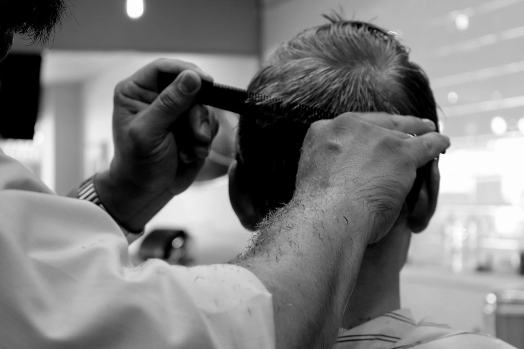Close-up of a barber combing and trimming hair