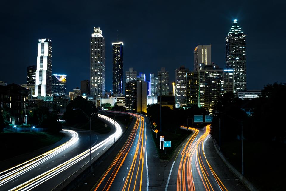 City skyline at night with light trails on the highway
